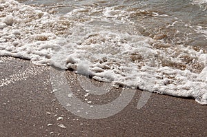 Black Sea. Water with waves. Mainly cloudy weather and sun rays. Blue and grey clouds. Before rain. Sand coast