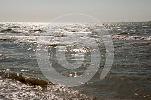 Black Sea. Water with waves. Mainly cloudy weather and sun rays. Blue and grey clouds. Before rain. Sand coast