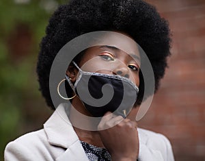 Black self-confident woman pulling down her face mask. Face covering is mandatory to wear in public during the COVID-19