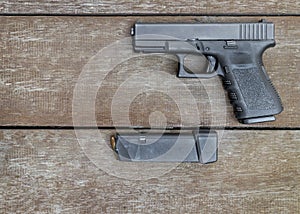 Black semi-automatic 9mm pistol and magazine on wooden background with Copy Space