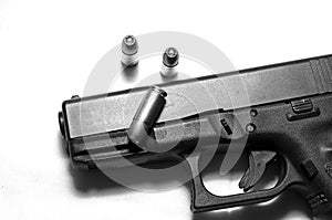 A black semi automatic 9mm pistol on a white background with three hollow point bullets