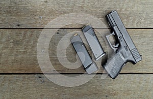 Black semi-automatic 9mm pistol and magazines on wooden background with Copy Space