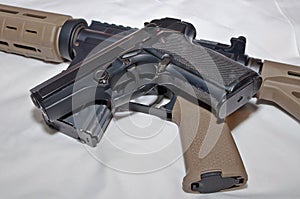 A black semiautomatic 40 caliber handgun on top of a black and brown 223 caliber AR-15