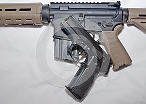 A black semiautomatic 40 caliber handgun on top of a black and brown 223 caliber AR-15