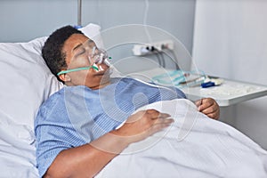 Black senior woman laying on bed in hospital room with oxygen support