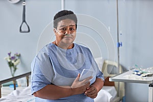 Black senior woman sitting on bed in hospital room with oxygen cannulas