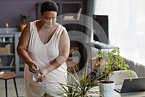 Black senior woman watering plants