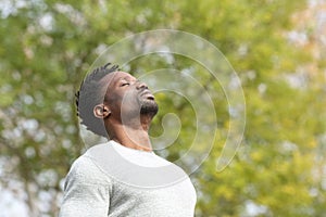 Black serious man breathing fresh air in a park