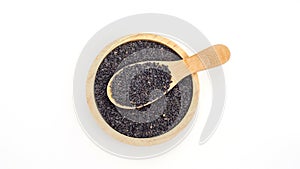 Black sesame seeds in a spoon and bowl on a white background