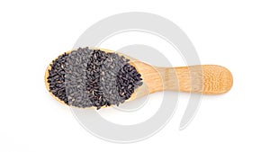 Black sesame seeds in a spoon on a white background