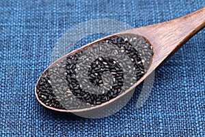 Black sesame seeds in a wooden spoon