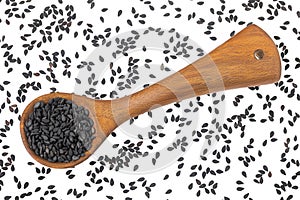 black sesame seeds in wooden spoon isolated on white background. Top view. Flat lay