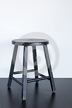 Black shabby stool on wooden surface