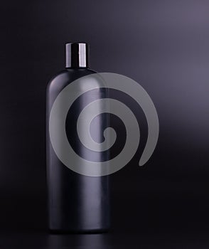 Black shampoo bottle on black background