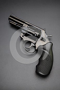 Black shiny revolver on black background