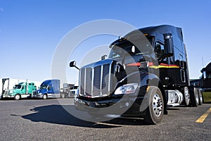 Black shiny stylish big rig semi truck tractor waiting for cargo