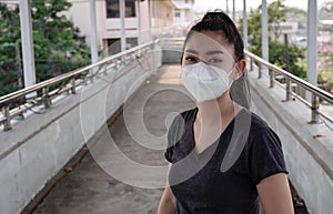 A Black shirt woman standing on putting on a respirator N95 mask to protect from airborne respiratory diseases as the flu covid-19