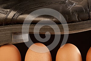 Black shoe walking on brown eggs