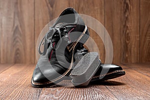 Black shoes one clean second dirty and brush on a wooden background. The concept of shoe shine, clothing care, services
