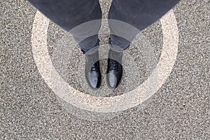 Black shoes standing in white circle on the asphalt concrete floor. Comfort zone or frame concept. Feet standing inside