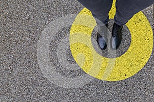 Black shoes standing in yellow circle on the asphalt concrete floor. Comfort zone or frame concept. Feet standing inside comfort