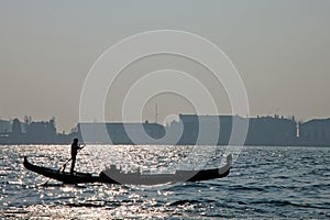 Black silhouette of a gondolier and his gondola on the Venetian Lagoon