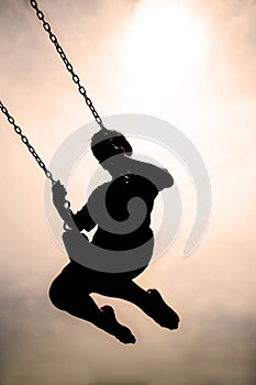 Silhouette of Child Swinging on PLaygroung Swingset photo