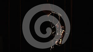 Black silhouette of male saxophonist musician playing golden alt saxophone on musical instrument. Cool saxophone player