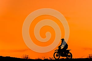 Black silhouette Motocross rider on a motorcycle in front of colorful sunset