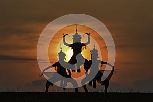 The black silhouette of three Manohra actors dancing in the park in the evening