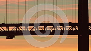 Black silhouette of a two-story suspension bridge against the backdrop of a sunset - a train passing on the lower level