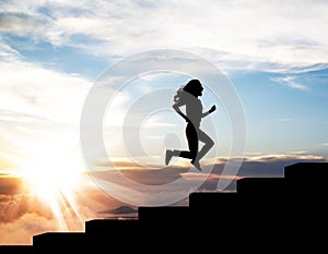 Black silhouette of woman running up on the staircase in sunset.