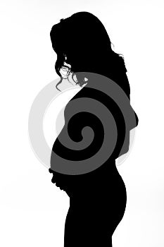 Black silhouette of a young pregnant woman on a white isolated background. Happiness in anticipation of a baby. Vertical