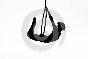 Black silhouette of a young woman posing on an air ring on an isolated white studio background. Female aerial acrobat