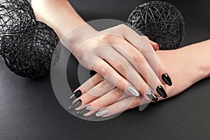 Black and silver manicure on black background. Female hands with black nails. Nail art and design