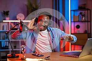 Black-skinned man in headphones making dancing movements while listening to music at home