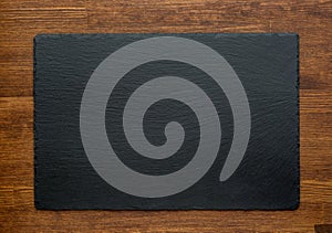 Black slate stone on wooden background, top view