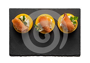 Black slate tray with three portions of polenta with salmon and cheese