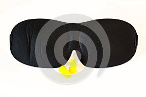 Black sleep mask on white ear plugs