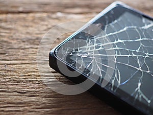 Black smartphone broken glass on old wooden board in the concept of mobile maintenance, accidental damage