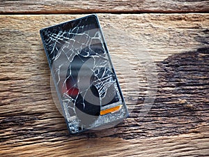 Black smartphone broken glass on old wooden board in the concept of mobile maintenance, accidental damage