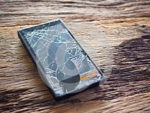 Black smartphone broken glass on old wooden board in the concept of mobile maintenance, accidental damage