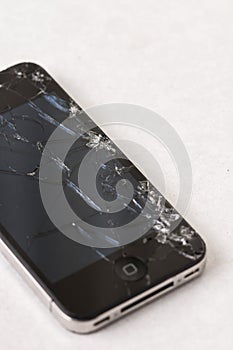 Black smartphone with crashed lcd touch screen above white marble background
