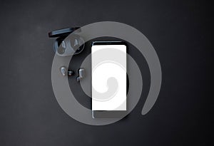Black smartphone and headset on black background photo