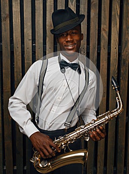 Black smiling jazz musician poses with saxophone