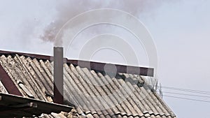 Black smoke coming out from rustic bathhouse chimney steel pipe, the concept of heating with low quality coal or rags