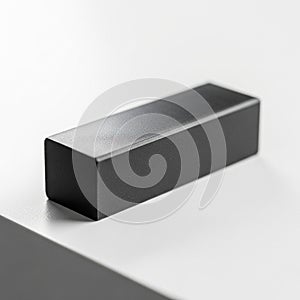 A black smooth rectangular block with sharp edges rests on a white surface
