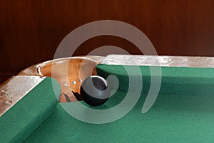 Black snooker ball by corner pocket