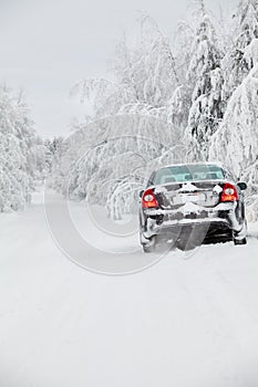 Black snowy car standing on winter road