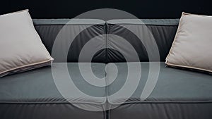 Black sofa with beige cushions filmed slowly in a black background. 4k video.